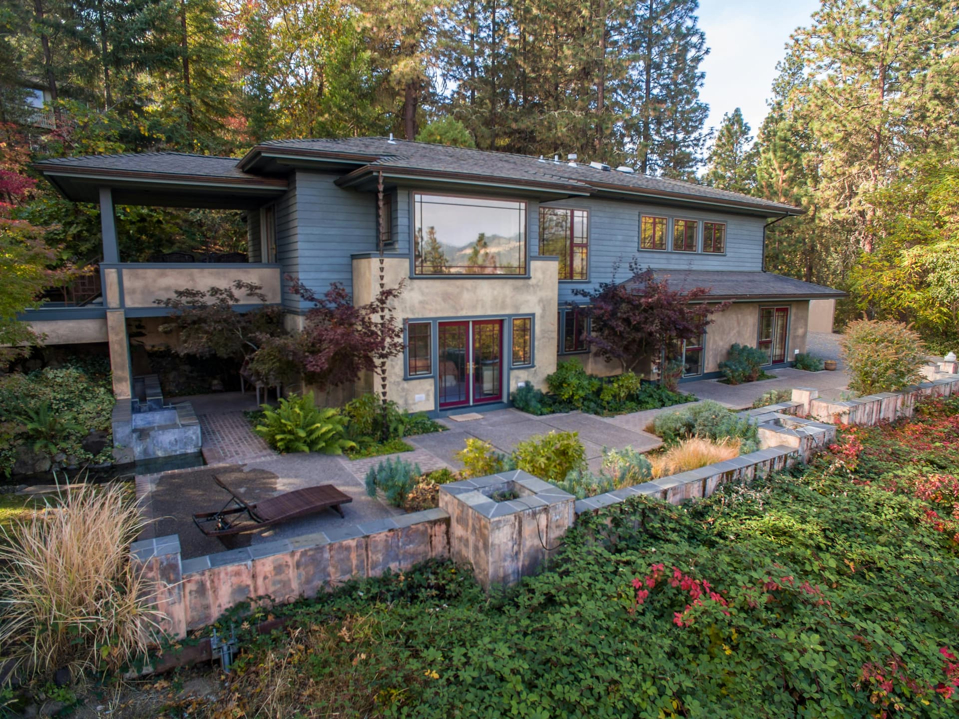 Contemporary Prairie-style home with terraced gardens and a water feature among pine and Japanese maple trees